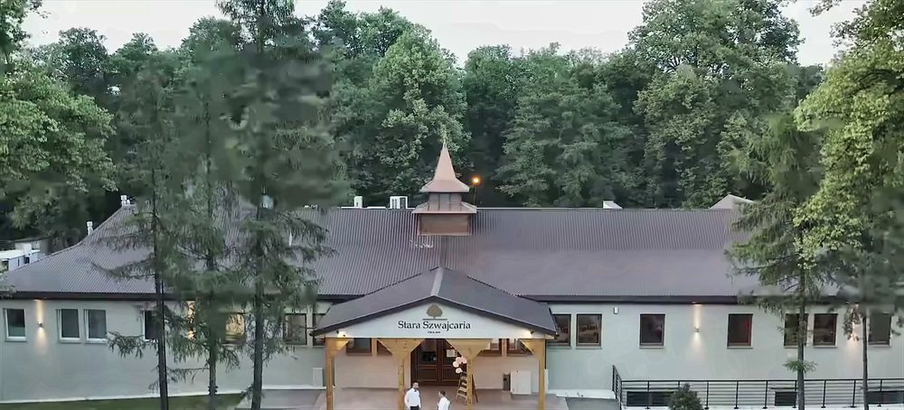 The Stara Szwajcaria building at dusk, surrounded by the trees of the park