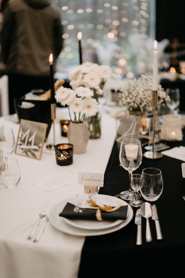 A place setting in close-up: candles, gold chargers and flowers