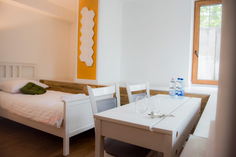 A twin room with a wooden floor, a desk and a large window