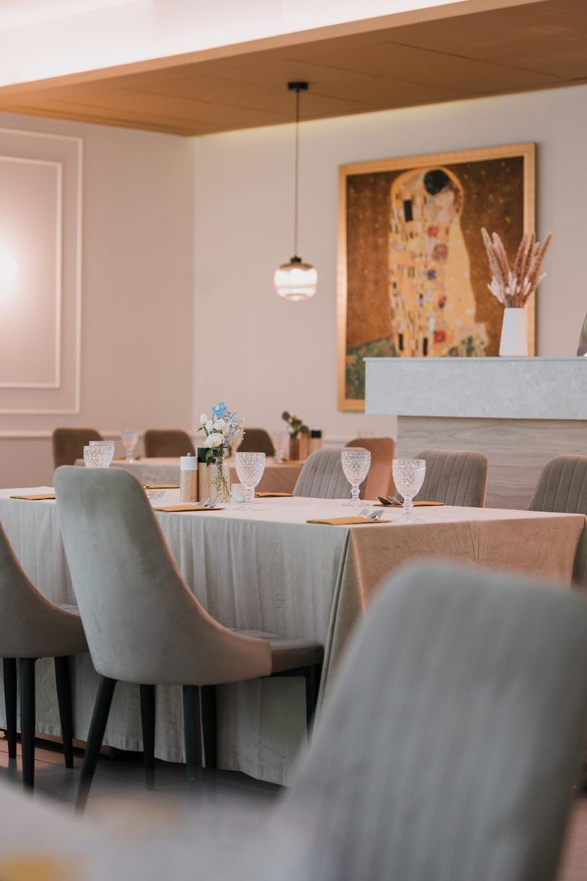 The dining room at Restauracja Park Szwajcaria: laid tables, grey chairs and a Klimt on the wall