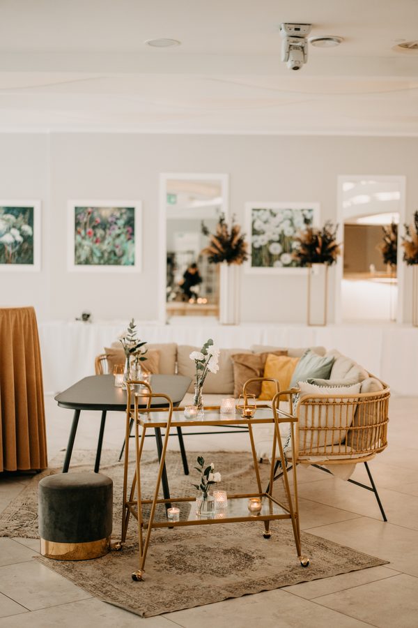 A seating corner in the Tarasowa hall: a wicker sofa, a drinks trolley and candles on the table