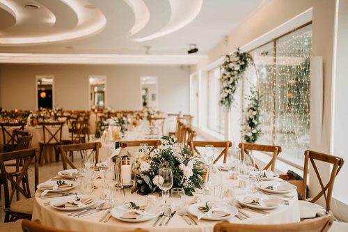 A round table laid beside a window hung with a curtain of lights